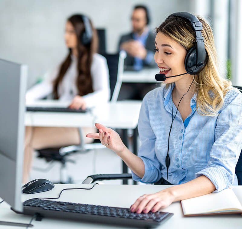 A smiling customer service representative talking with a customer on the phone.