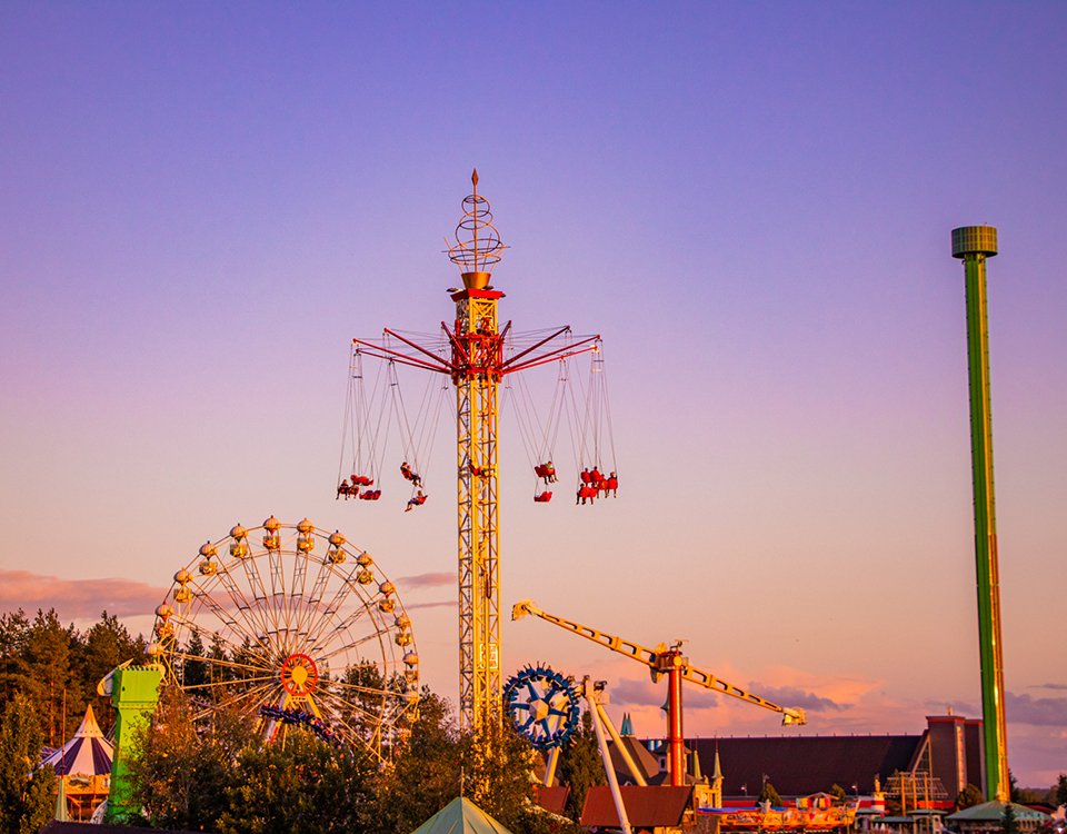 Visitors enjoying amusement rides at PowerPark in the evening sunlight.