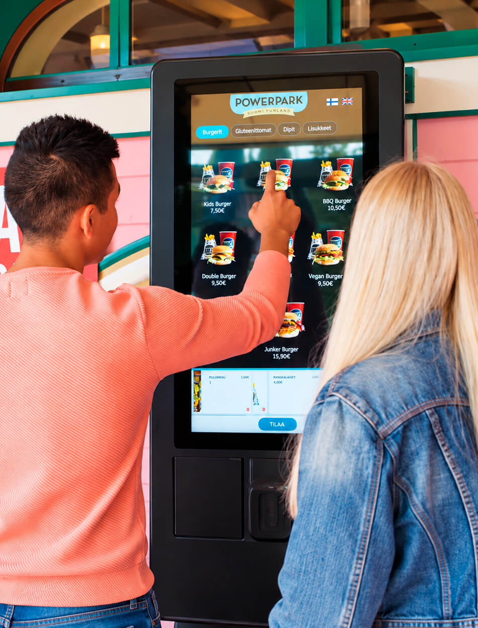 Amusement park visitors choosing their meals at a self-service kiosk in a PowerPark restaurant, without unnecessary queuing.