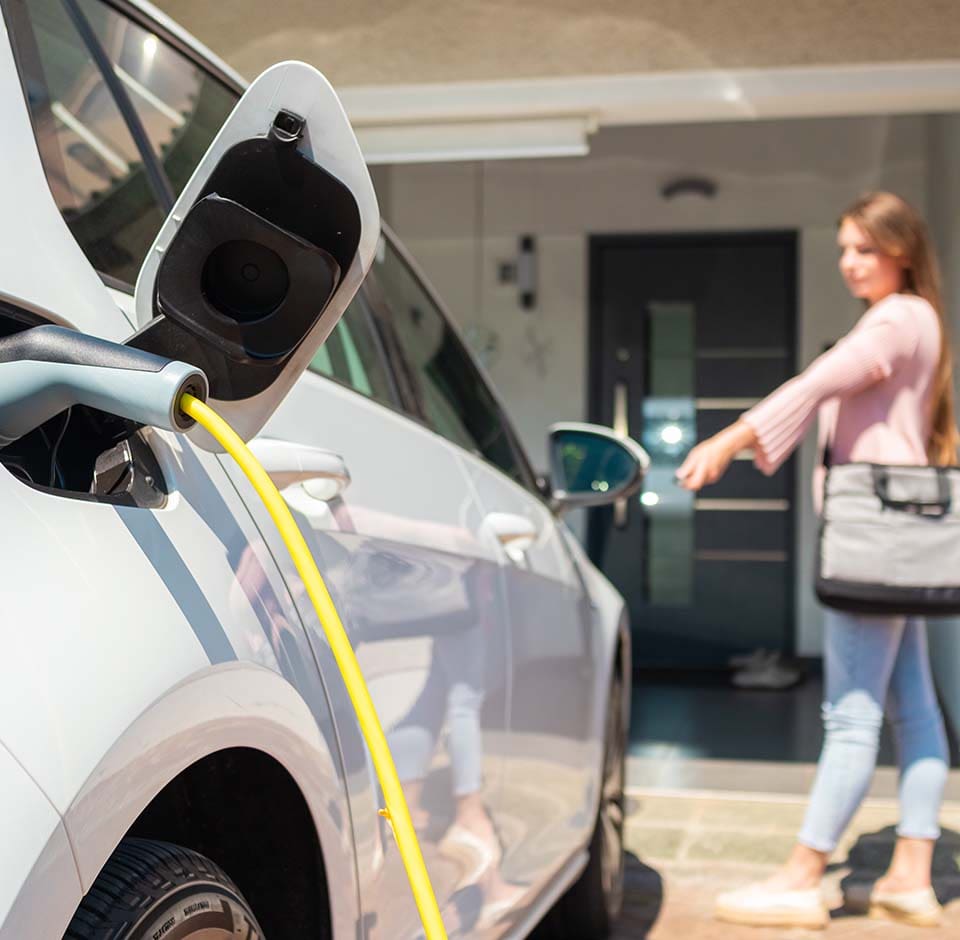 A woman charging an electric vehicle at home.