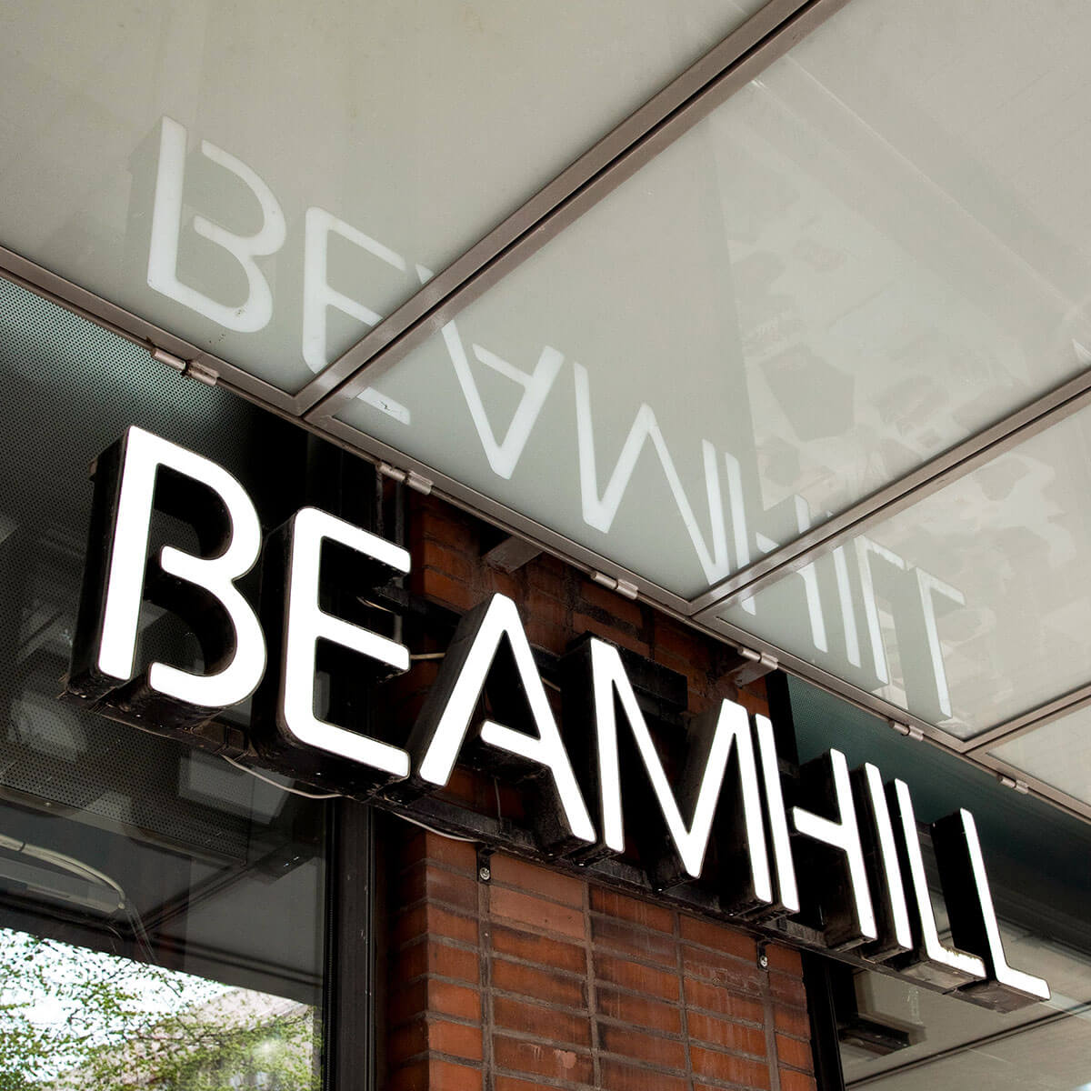 Beamhill valokyltti seinällä sekä valokyltin heijatus katossa
