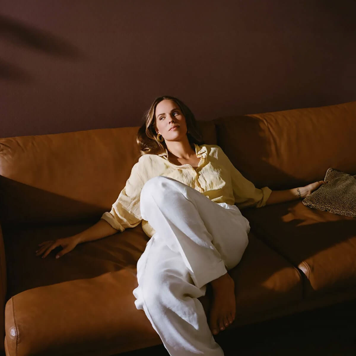 Woman lying on a brown leather couch