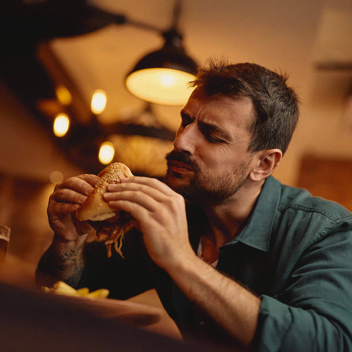 Mand spiser hamburger på en fastfoodrestaurant, der bruger Commerce Cloud POS-systemet