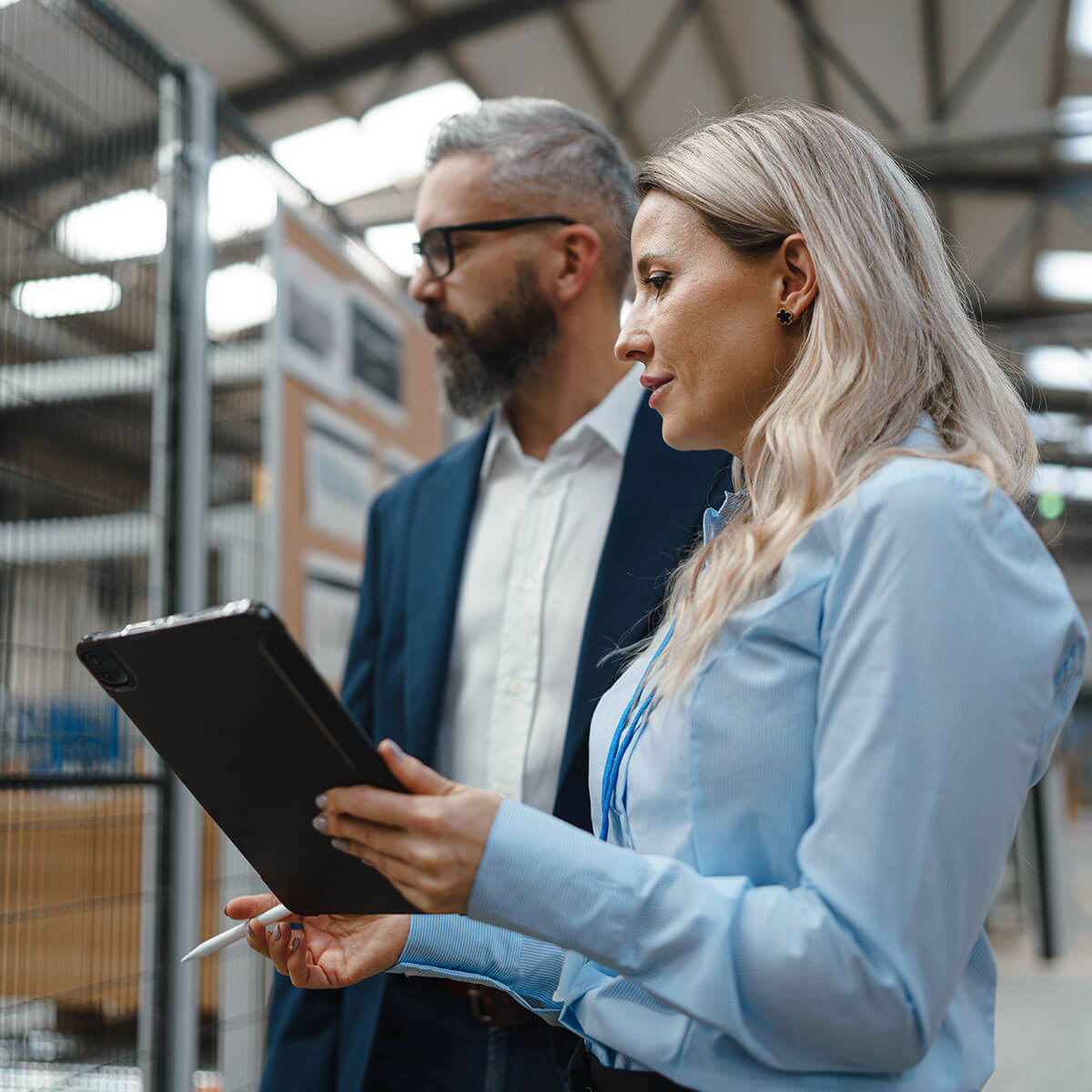 Two professionals reviewing data on a tablet in an industrial facility