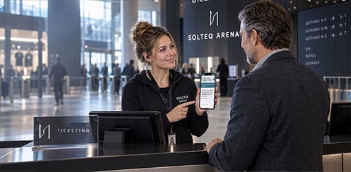 Solteq Arenan työntekijä esittelee Solteq Commerce Cloudin Buddy-tekoälyavustajaa älypuhelimella areenan johtajalle lipunmyyntipisteellä.