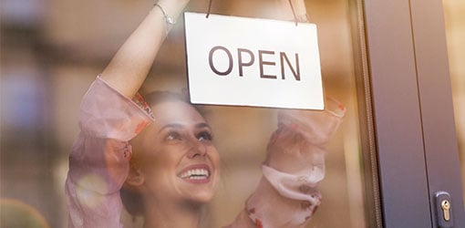 Restaurant owner hanging open sign to a glass door - online shop is open 24/7
