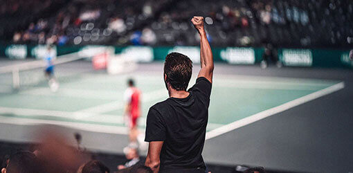 Tennisfan som njuter av en match på en sportarena som stöds av ett molnbaserat POS-system för handel
