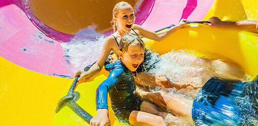 Äiti ja poika laskevat vesiliukumäessä teemapuistossa.