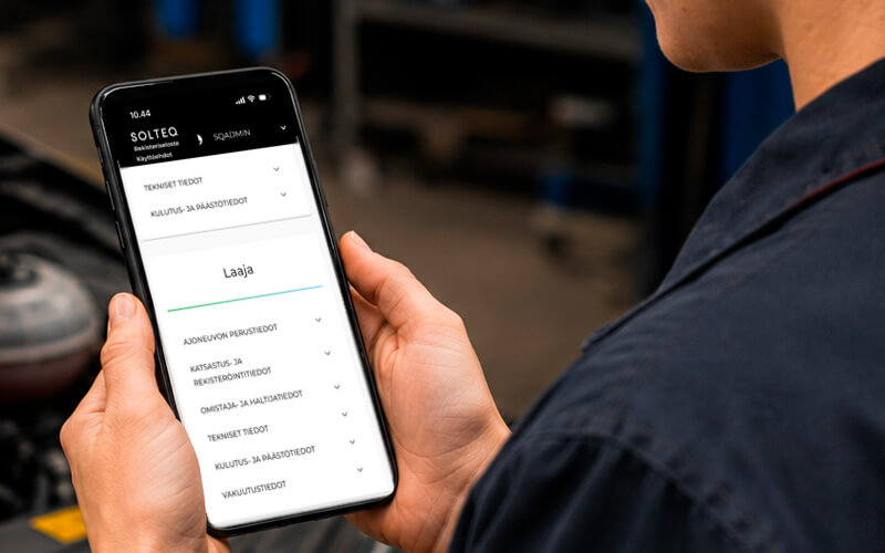 Close-up of a Traficom vehicle data query on a mobile phone screen in an auto repair shop.