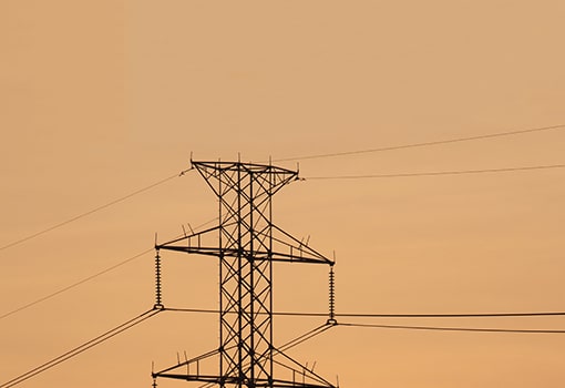 Top of the electric pole against orange sky