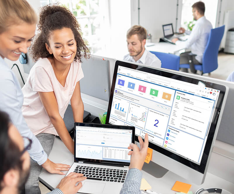 Hymyilevä asiakaspalvelutiimi tarkastelee asiakkaan tietoja Solteq Utility Cloud -järjestelmästä.
