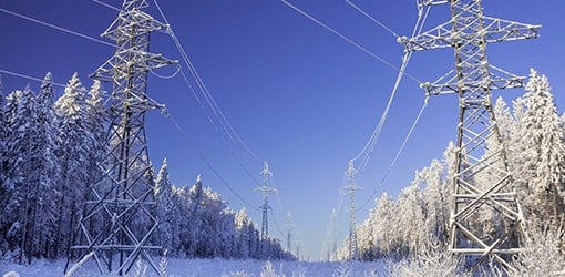 Sähköverkkoa lumisen metsän keskellä aurinkoisena talvipäivänä.
