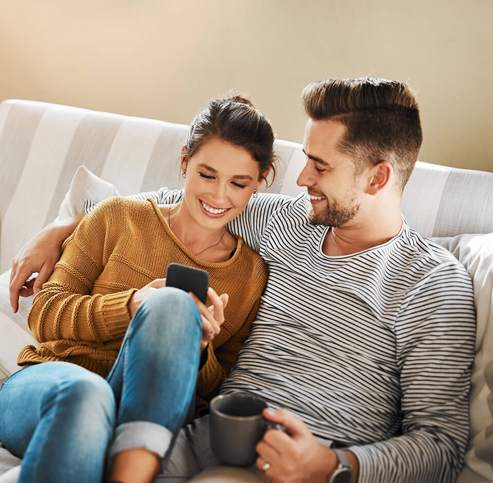A smiling couple checking their consumption data on a mobile phone via a modern self-service.