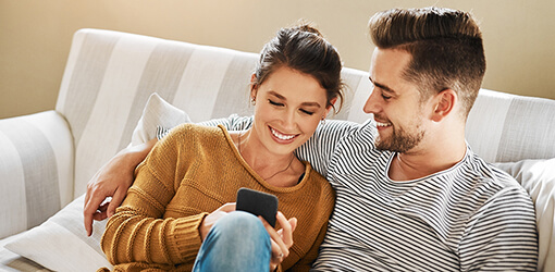 Smiling customers accessing their information through self-service on a mobile phone