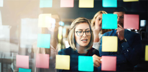 Woman writing notes to post-it pads how to navigate Composable Commerce, Headless Commerce, and Microservices