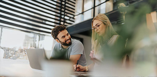 Woman and man discussion by a table and making notes of their composable commerce strategy