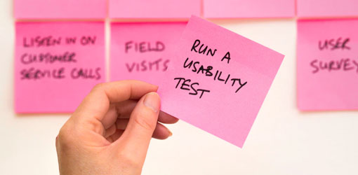 Post-its on a wall and a hand holding one post it saying run a usability test