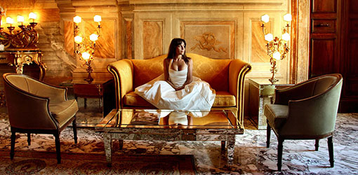 Woman sitting on a luxury couch in an elegant white dress - Moving from fine dining to couch dining