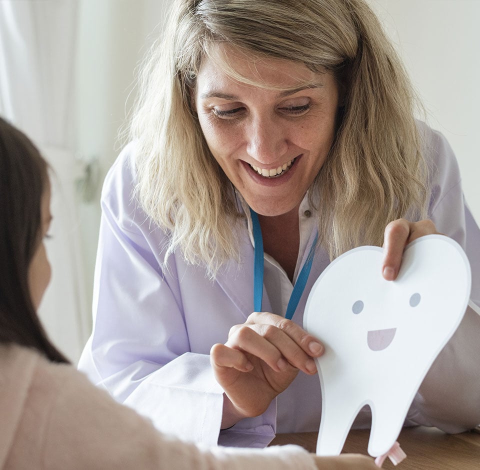 Kvindelig tandlæge, der viser et tandbillede til en barnepatient