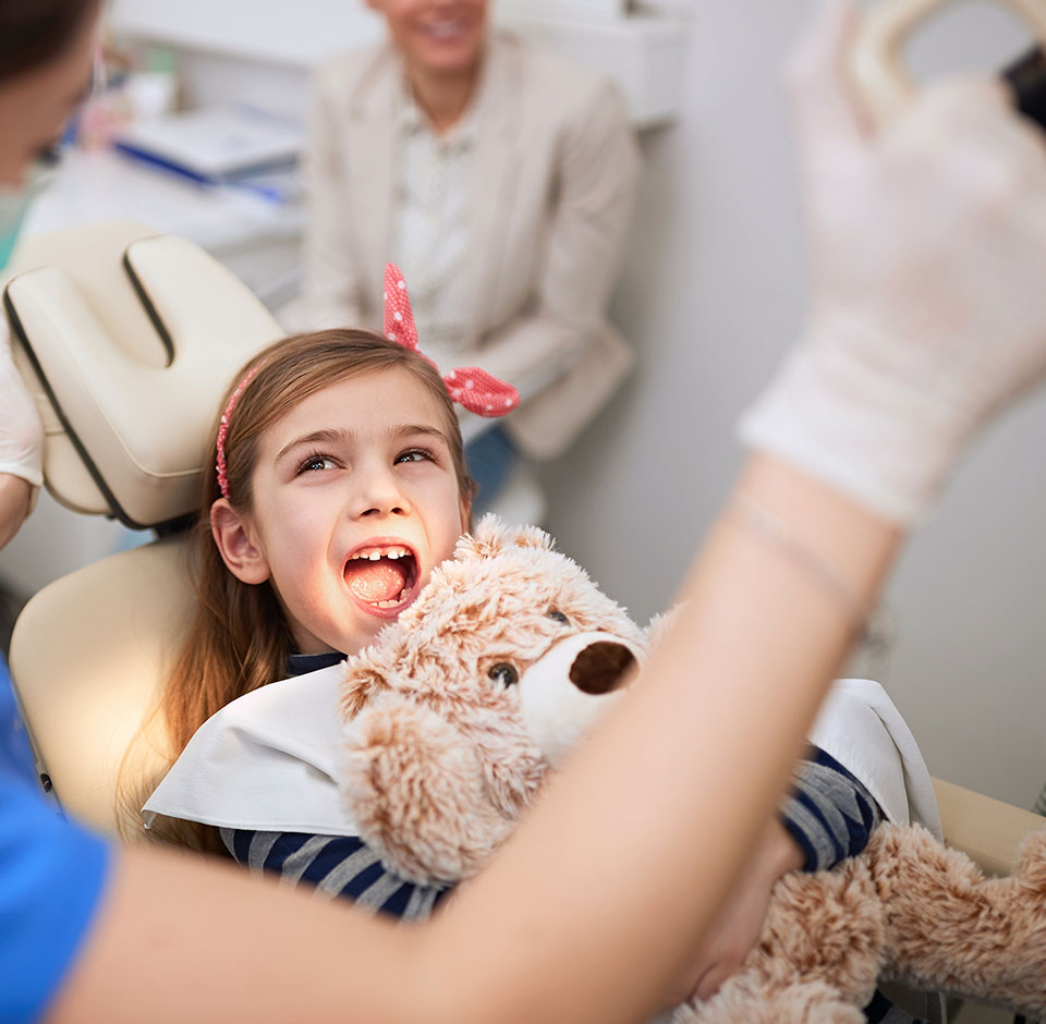 Pige med en bamse på en tandlæge stol