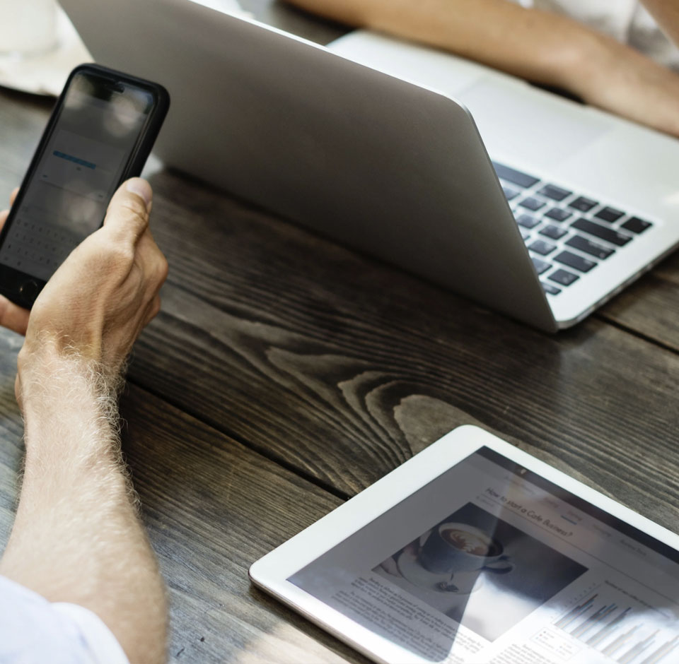 Mann og kvinne som forhandler kaffe med laptop og mobiltelefon