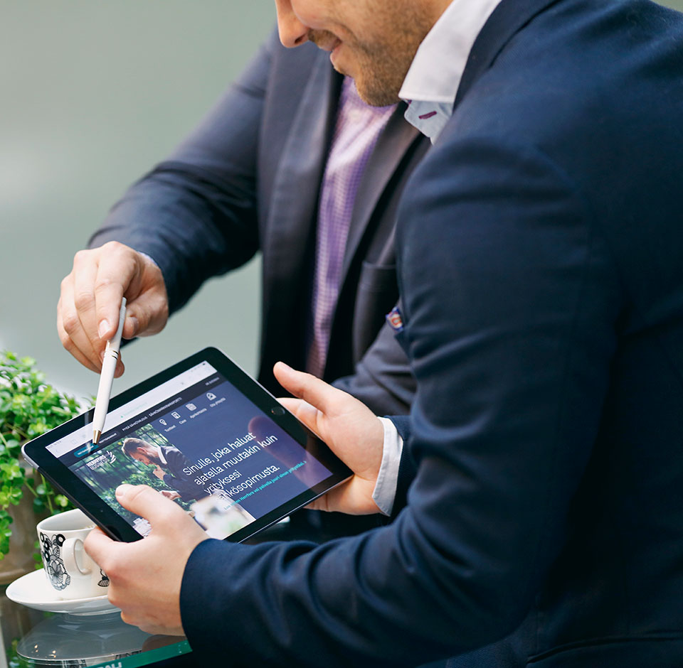 Two people are viewing the Herrforss website on a tablet.