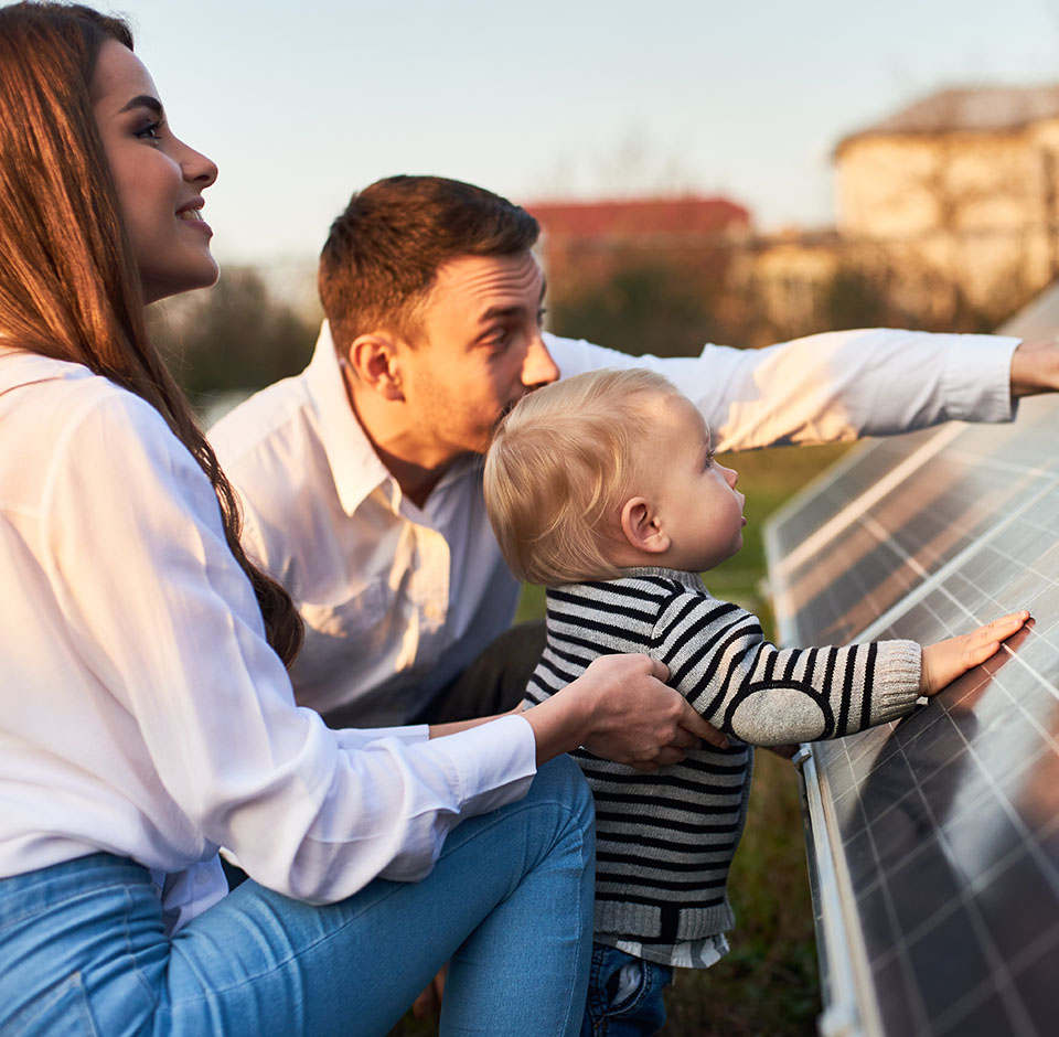 Mies, nainen ja pieni lapsi tutkivat aurinkopaneelia.