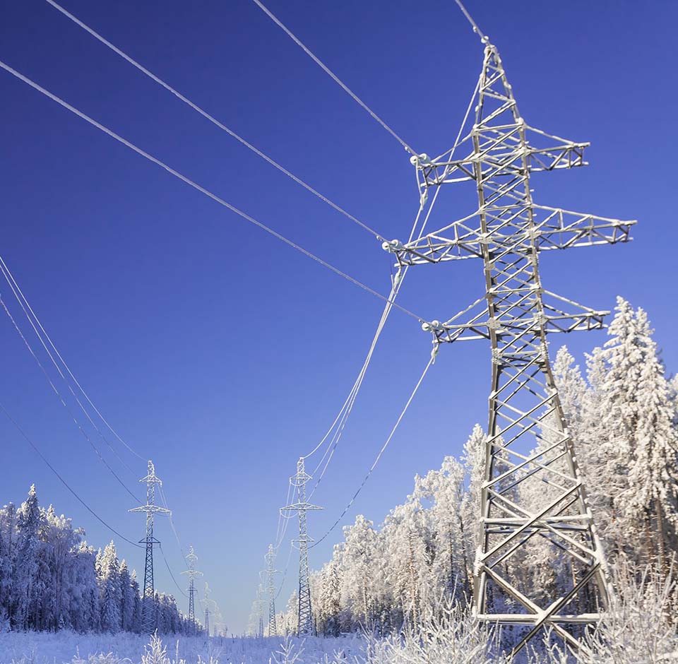 Power line in a winter landscape against a blue sky.