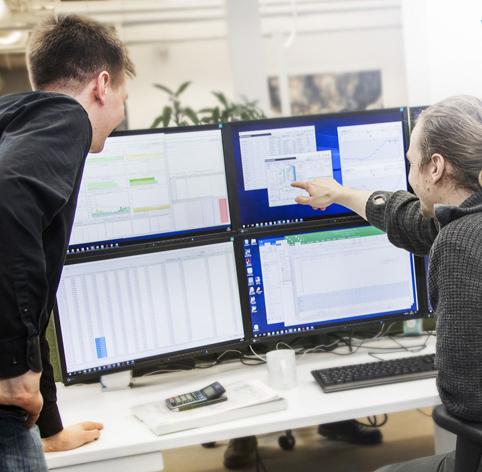 Two people examine a report on the screen.