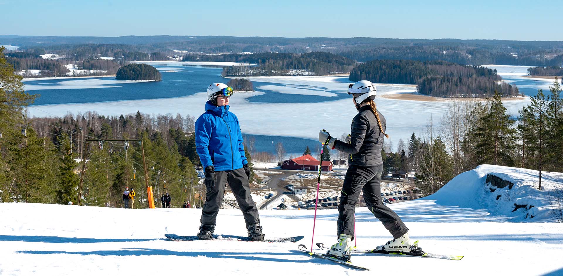 Snowboarder and skier at the top of Ellivuori's ski slope.