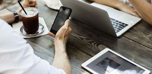 Mand og kvinde forhandler om kaffe med bærbar computer og mobiltelefon på et bord