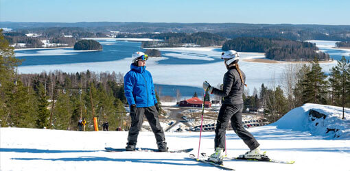 Snowboarder and skier at the top of Ellivuori's ski slope.