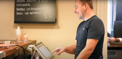 Joona Terävä, System Specialist, VoiVeljet is using POS device behind the counter in a restaurant.