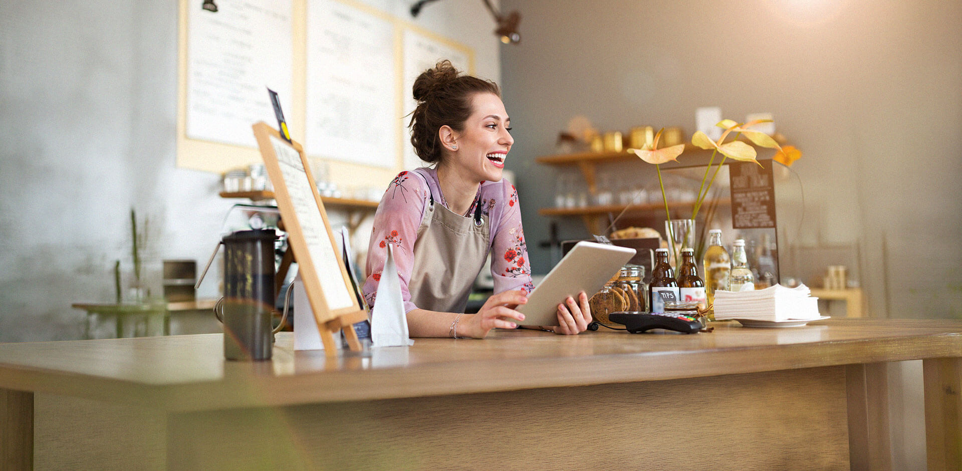 Restaurant staff member using a tablet POS behind the counter, illustrating modern hospitality operations and efficient order management