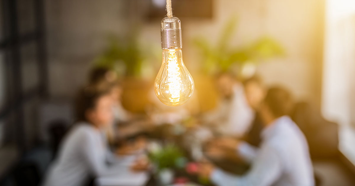 A group of people listening to consulting services at a table, in front of an electric lamp.