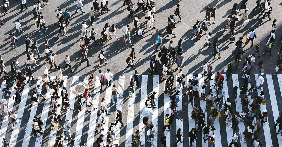 A group of people walking on a crosswalk.