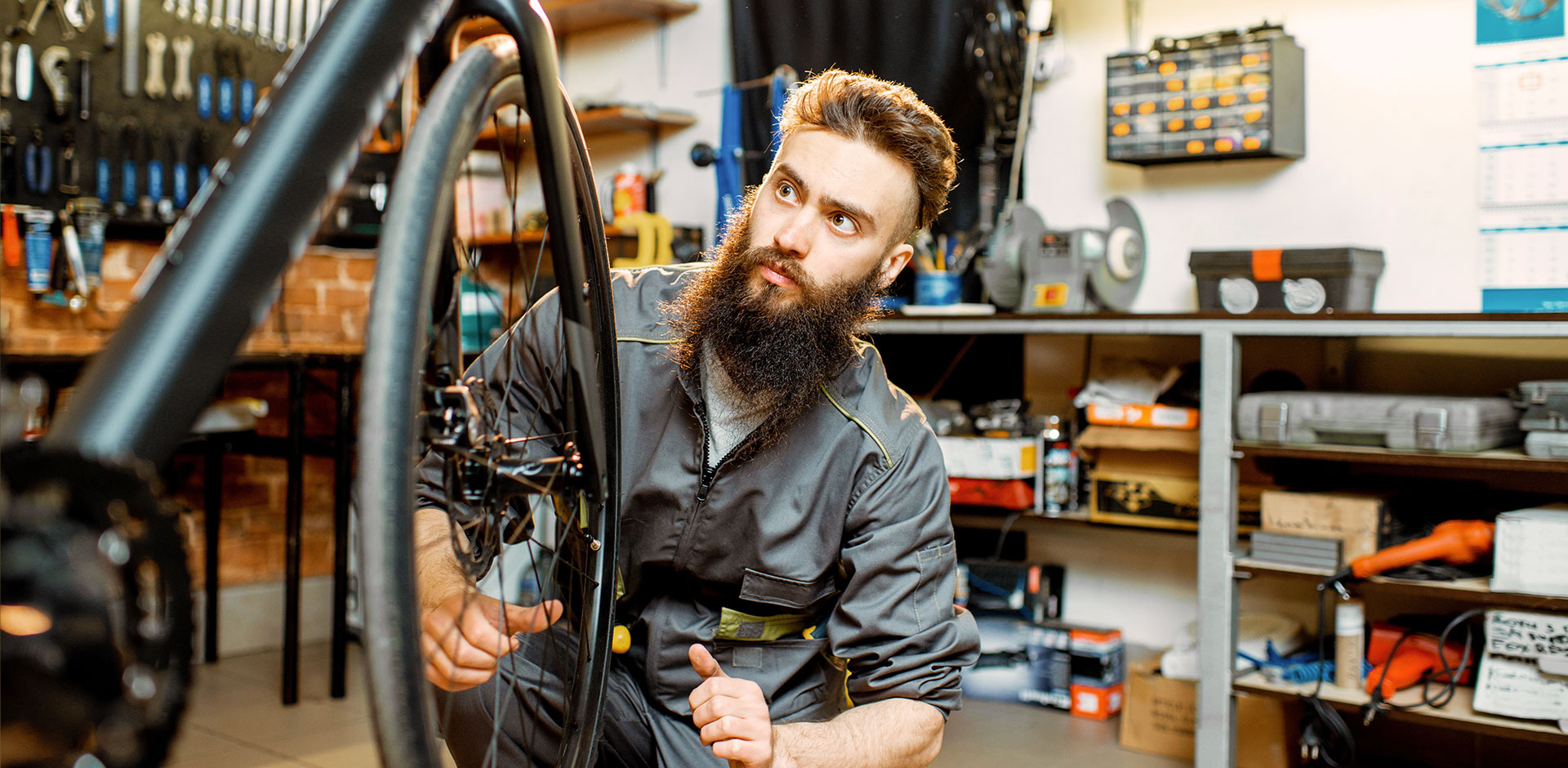 An employee of a bicycle shop repairs a bicycle in the shop.