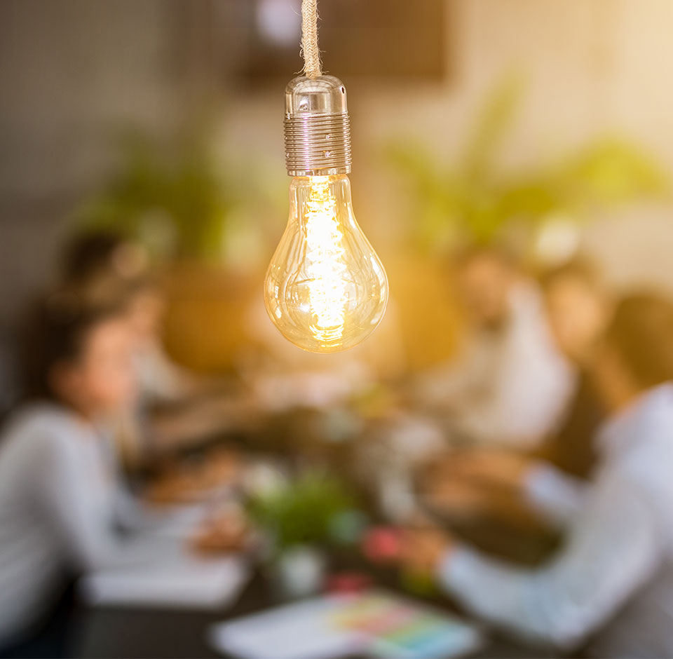 En grupp människor som konsulterar konsulttjänster vid ett bord, framför en elektrisk lampa