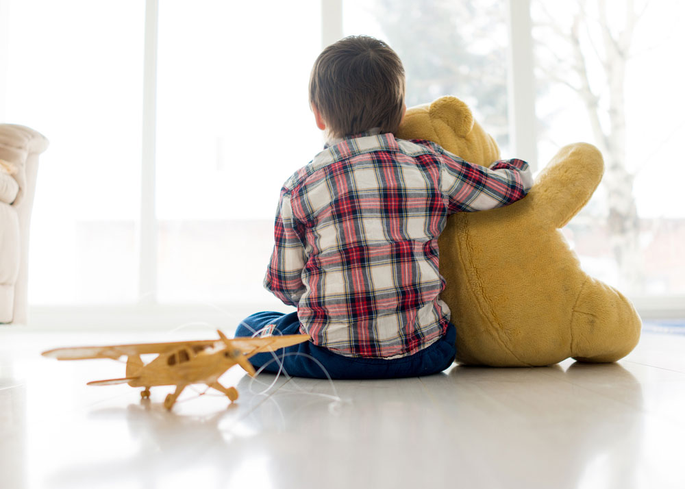 Portræt af barn sidder i stuen med bamse