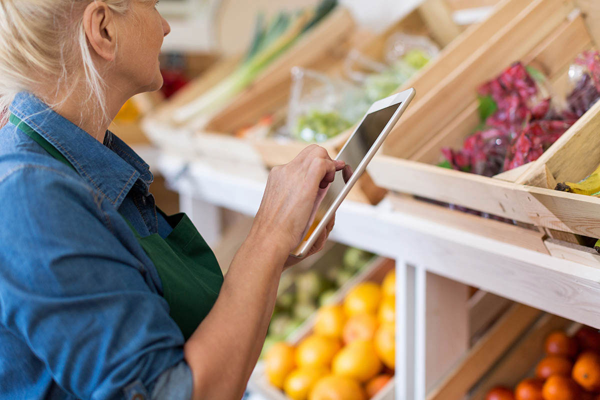 The shopkeeper examines information about the supply chain management system on a tablet in the store.