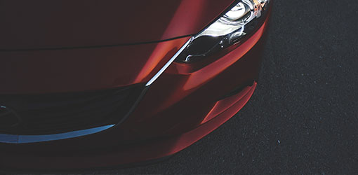 Headlight of a red sports car in a close up.