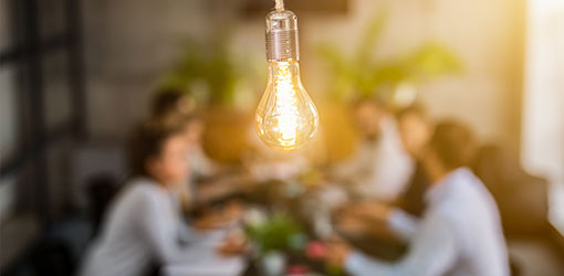 A group of people hearing about consulting services at the table, with an electric lamp in front.