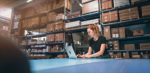 Woman working with laptop on large e-commerce warehouse operated by HCL Commerce e-commerce platform
