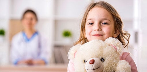Solteq Care - A happy girl with teddy bear at doctor's appointment