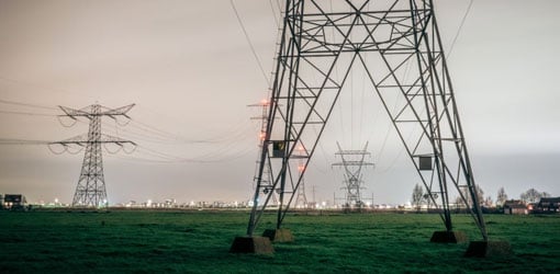 inWorks - Power lines run through the grassy field, with city silhouette in the background