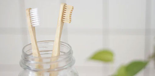 Solteq Tand - To tandbørster i en klar glasskrukke med flisebelagt baggrund