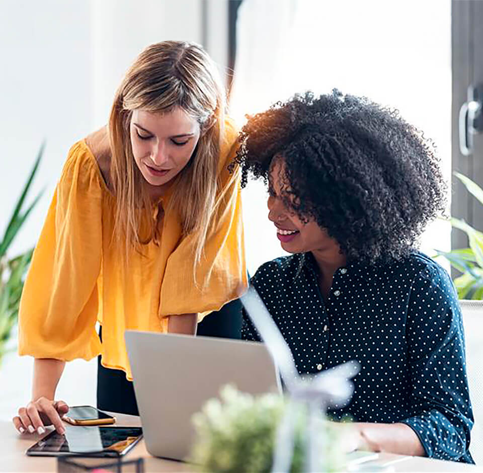 Smilende kundeservicemedarbejdere gennemgår kundedata i det brugervenlige Solteq Utility Cloud kundedatasystem.